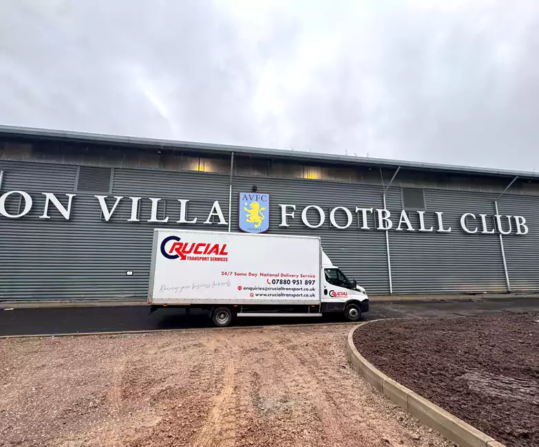 Sign-written Crucial Transport Luton van parked outside Aston Villa football ground during a commercial large item delivery